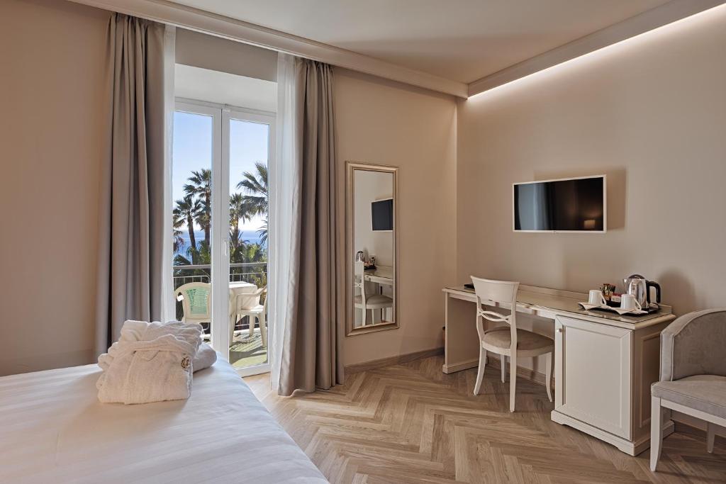 une chambre d'hôtel avec un lit et un bureau dans l'établissement Hotel Paradiso, à Sanremo