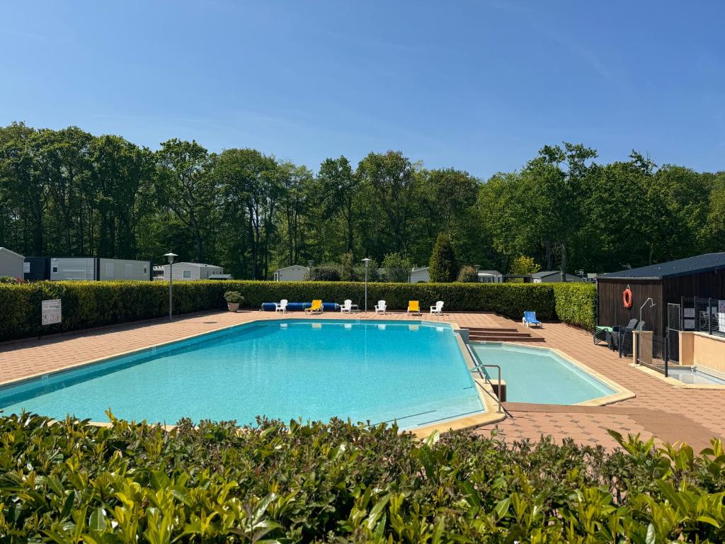 une grande piscine avec des chaises et des arbres dans l'établissement Mobil-home tout confort, à Dinard