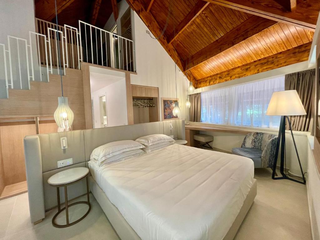 une chambre avec un grand lit blanc et une lampe dans l'établissement La Bussola Beach Hotel, à Punta Ala