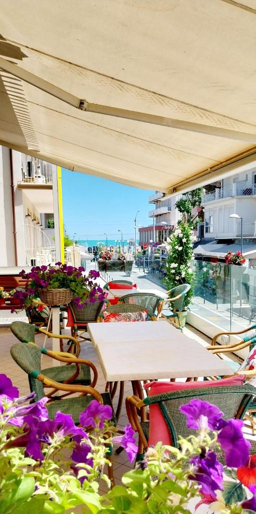 un patio extérieur avec tables, chaises et fleurs dans l'établissement Hotel Brotas, à Rimini