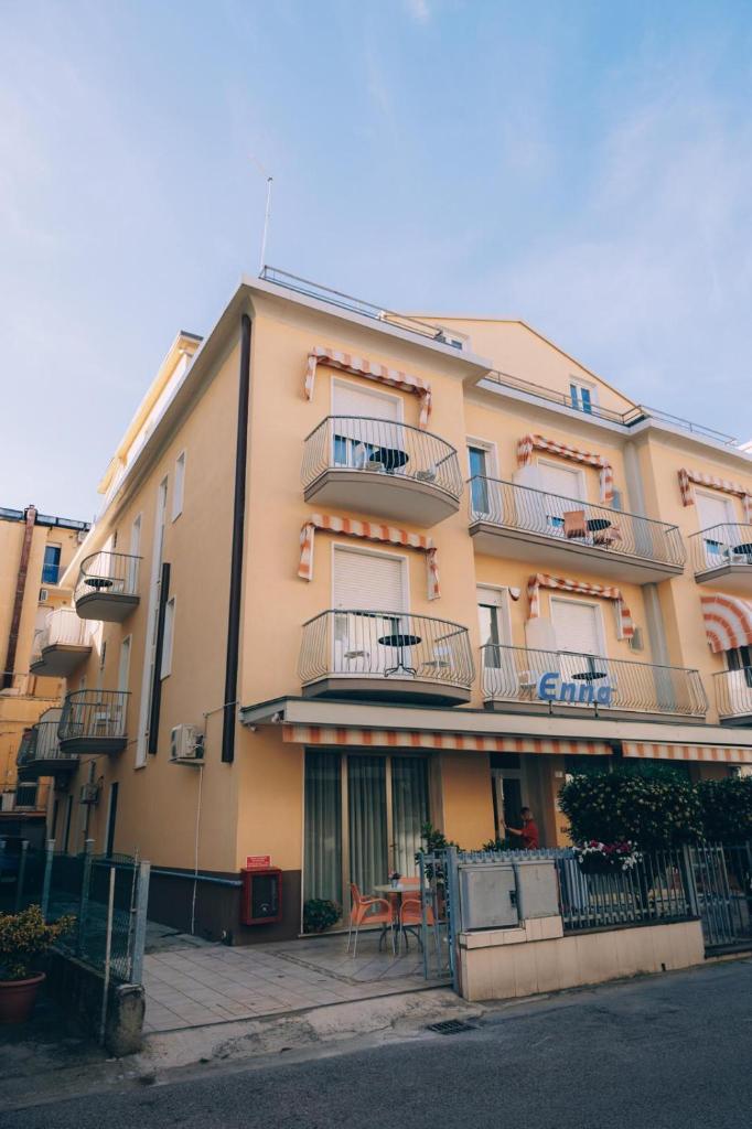 un bâtiment avec des balcons et une table devant dans l'établissement Hotel Enna Rimini, à Rimini