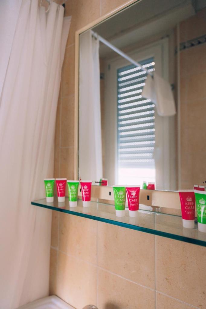 une salle de bain avec des tasses vertes et rouges sur une étagère dans l'établissement Hotel Enna Rimini, à Rimini