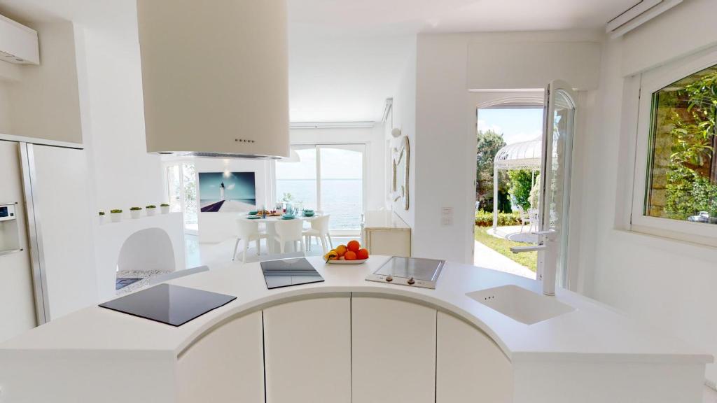 une cuisine avec comptoirs blancs et une grande fenêtre dans l'établissement Villa Flora, à Manerba del Garda