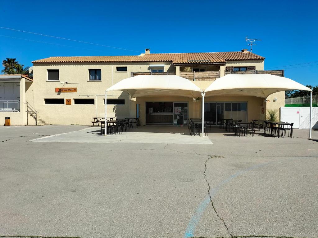 un bâtiment avec des tables et des parasols dans un parking dans l'établissement Le mobil-home d'Amélie, entre mer et garrigue, à Vic-la-Gardiole