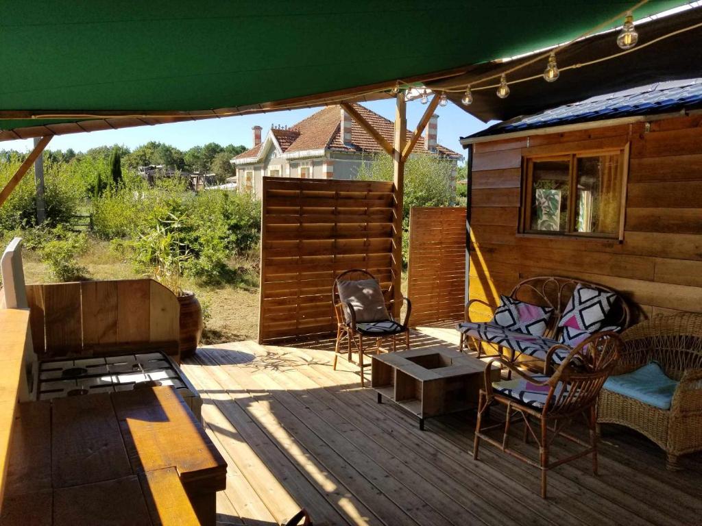 un patio avec des chaises, une table et un parasol dans l'établissement La Tiny-house et la roulotte des sables, à Le Porge 10 autres photos
