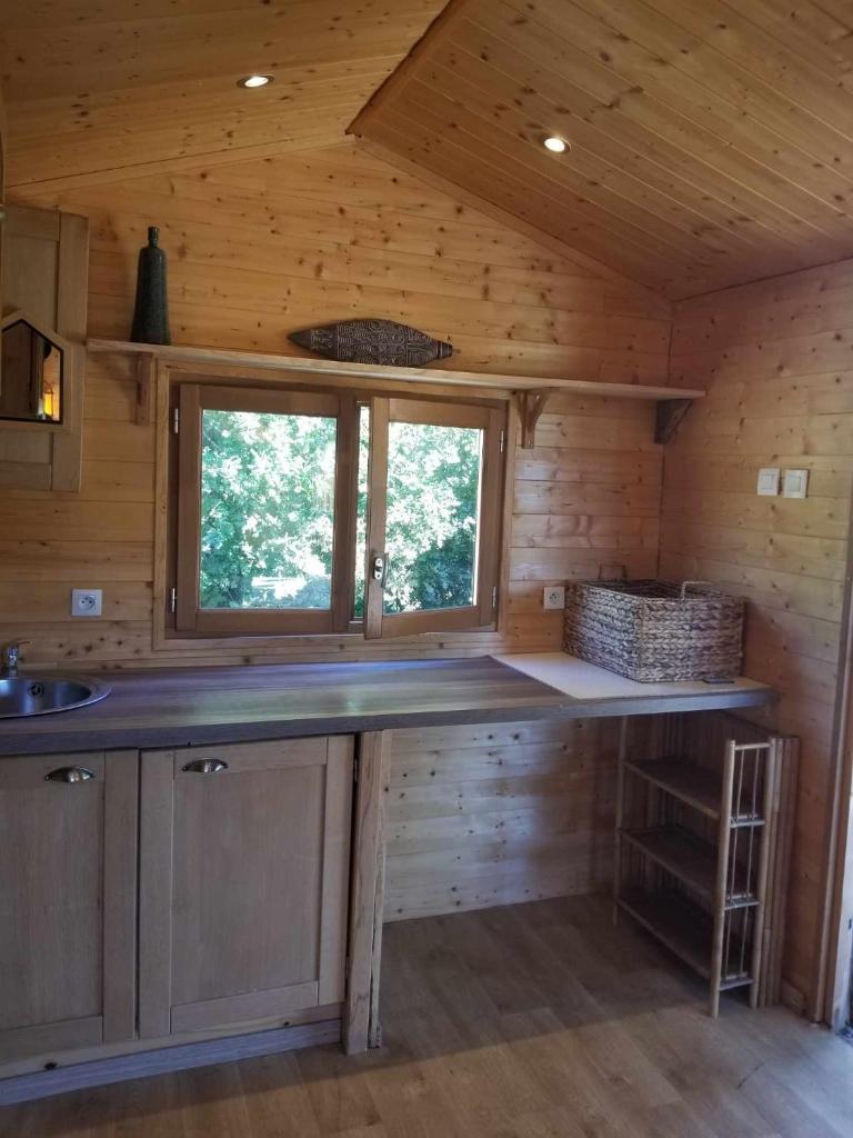 - une cuisine dans une cabane en rondins avec un comptoir dans l'établissement La Tiny-house et la roulotte des sables, à Le Porge