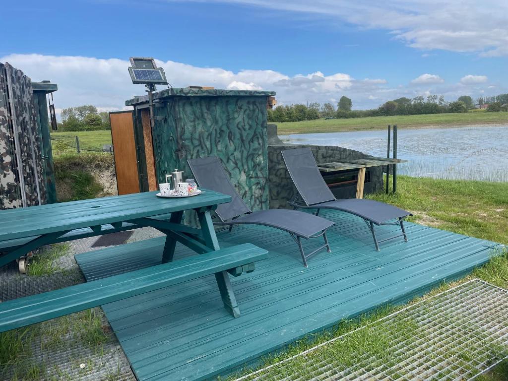 - une table de pique-nique et des chaises sur une terrasse au bord de l'eau dans l'établissement Nature en Somme, à Quend
