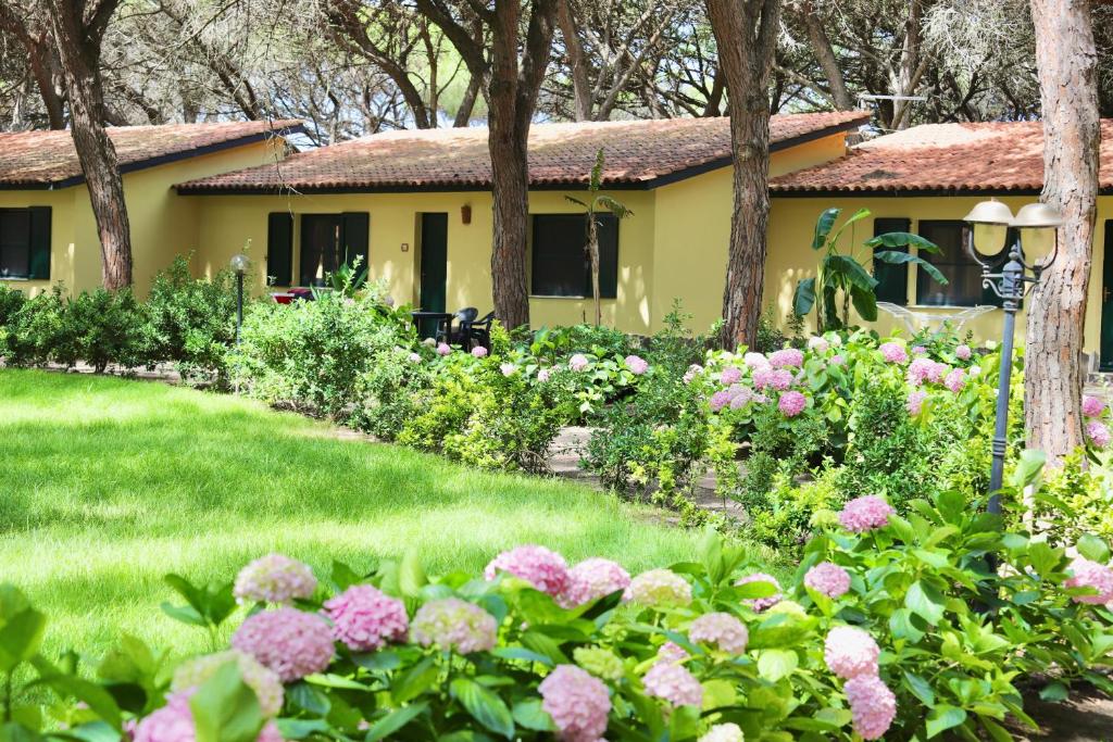 un jardin avec des fleurs roses en face d'une maison dans l'établissement Residence with swimming-pool in Arborea just 300 meters from the beach, à Arborea