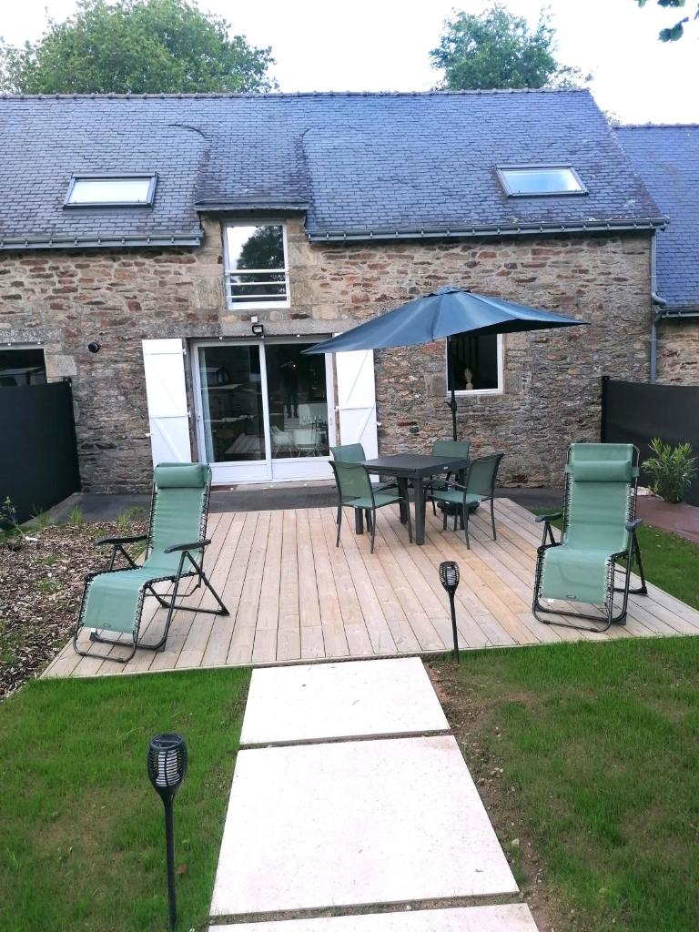 un patio avec une table, des chaises et un parasol dans l'établissement Les Gîtes de l'étang de la forêt, à Brandivy