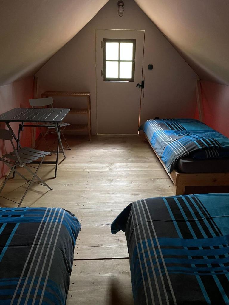 une chambre mansardée avec deux lits et une table dans l'établissement Camp du Père Castor, à Simard
