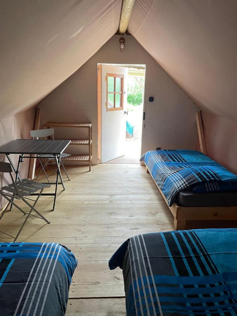 Cette chambre mansardée comprend 2 lits et une table. dans l'établissement Camp du Père Castor, à Simard