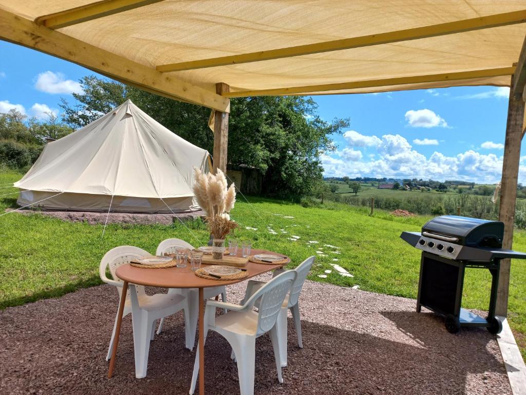 une table et des chaises avec un barbecue et une tente dans l'établissement Tipi du petit villers, à Le Brethon