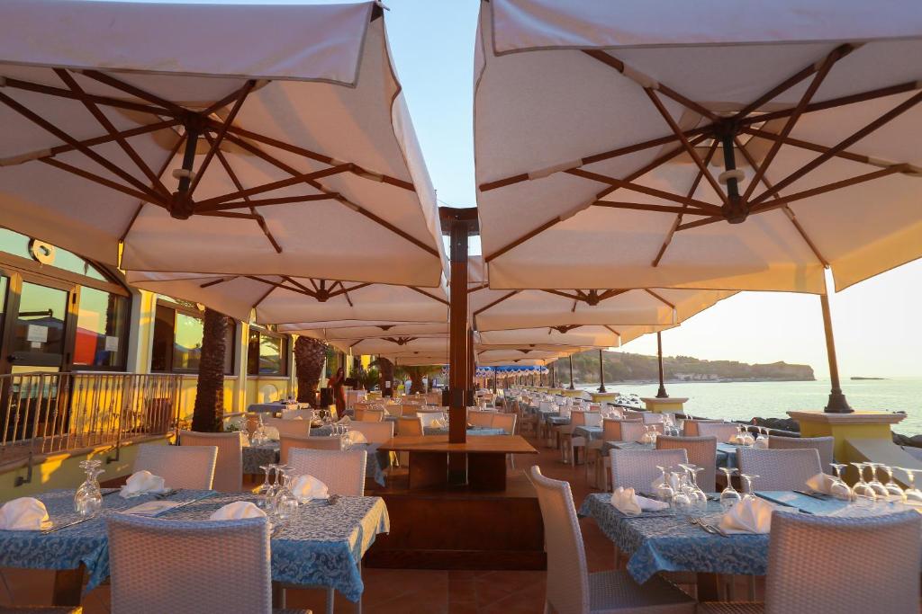 un restaurant avec des tables, des chaises et des parasols dans l'établissement Villaggio Hotel Lido San Giuseppe, à Briatico