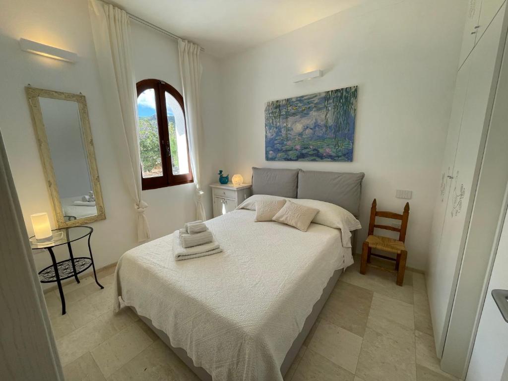 une chambre blanche avec un lit et une chaise dans l'établissement Villa with private pool, amazing sea panorama and private garden, à Domus de Maria 58 autres photos