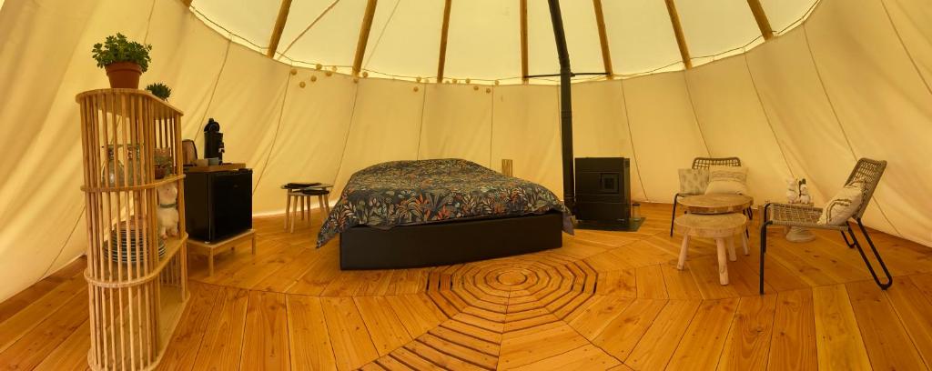 une chambre dans une tente avec un lit et une table dans l'établissement Nuit insolite en Tipi avec bain nordique privatif, petits déjeuners inclus, à Médonville