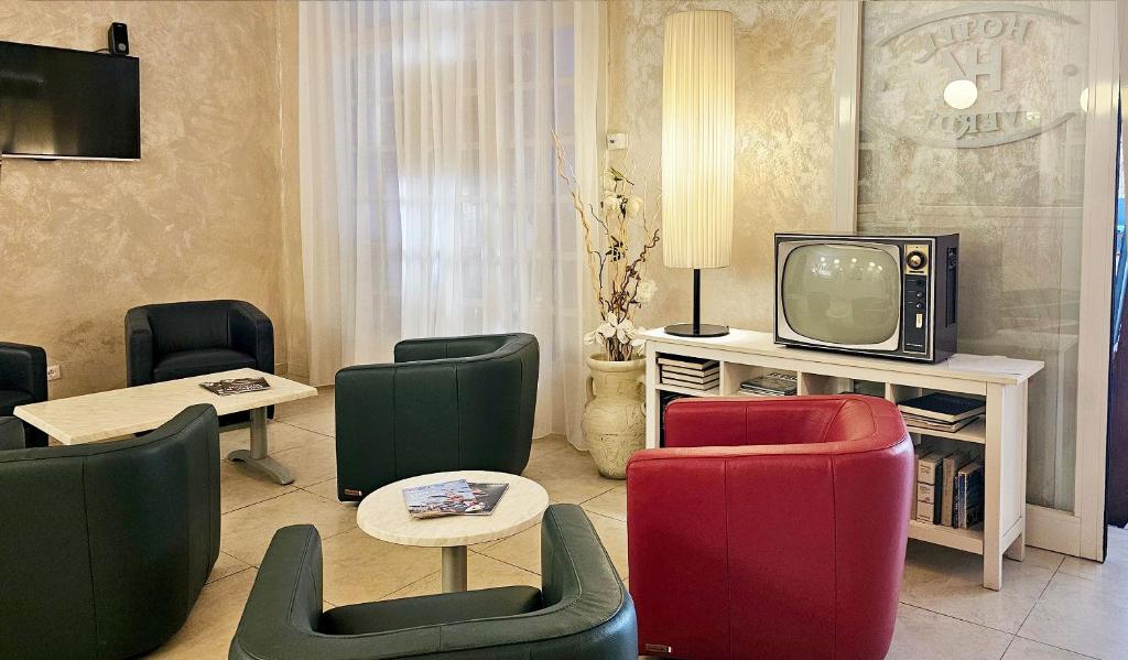d'un salon avec des chaises colorées et une télévision. dans l'établissement Hotel Verdi, à Lido di Jesolo