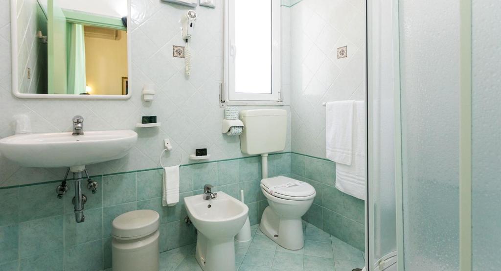 une salle de bain avec un lavabo, des toilettes et un miroir dans l'établissement RESORT BAMBY, à Cervia