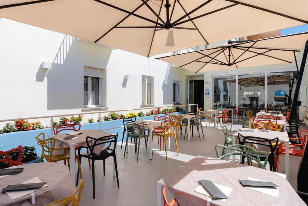 un restaurant vide avec des tables, des chaises et des parasols dans l'établissement Hotel Nina, à Marina di Bibbona