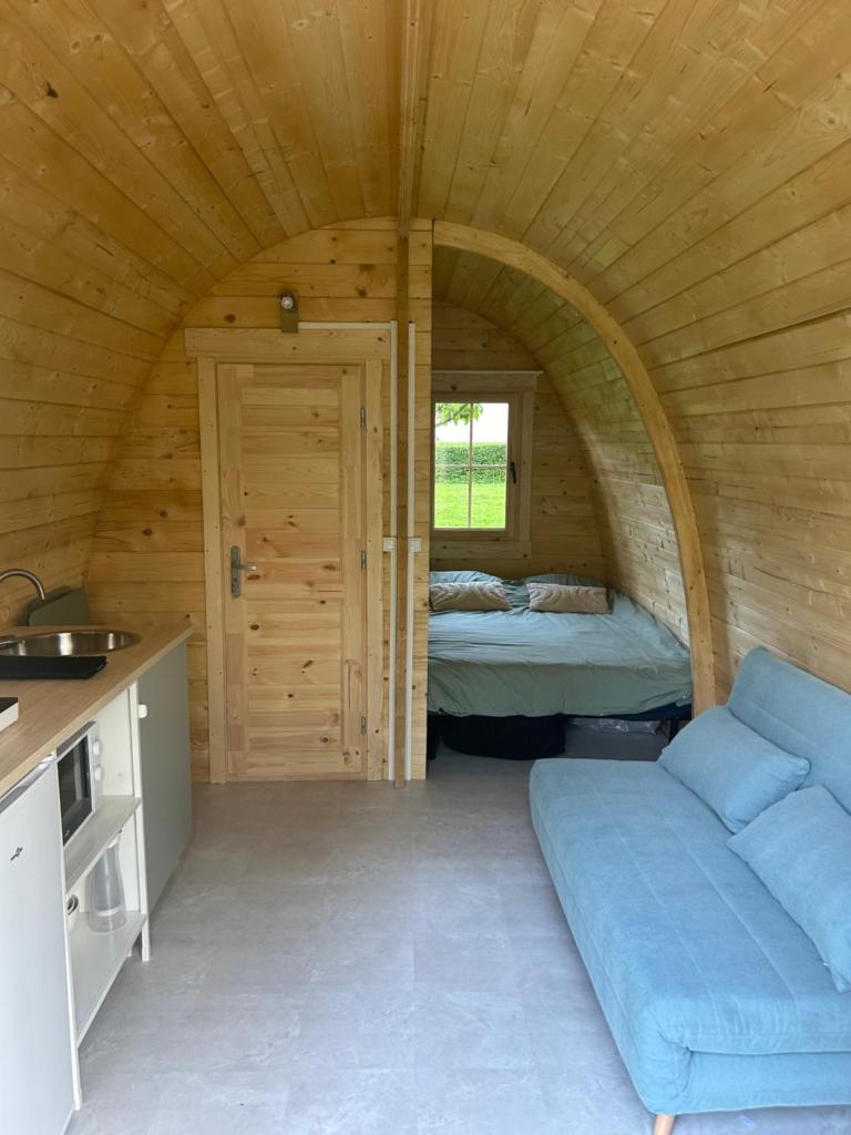 - une chambre avec un canapé et un lit dans une cabine dans l'établissement La pod de mon jardin, à Prix-lès-Mézières