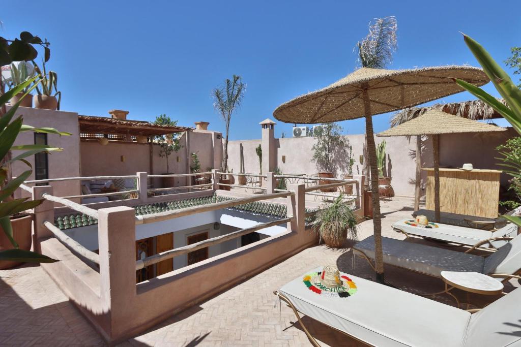 - une terrasse avec 2 tables et un parasol dans l'établissement Riad Darchica, à Marrakech