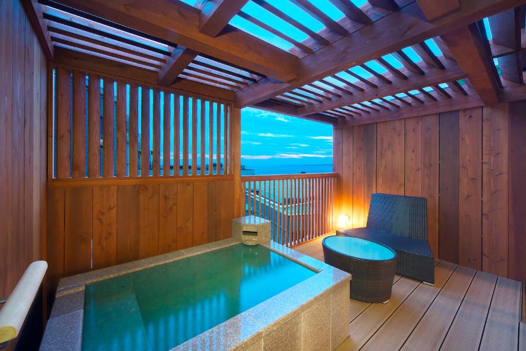 un jacuzzi dans une pièce en bois avec une chaise dans l'établissement Umiusagi, à Higashiizu