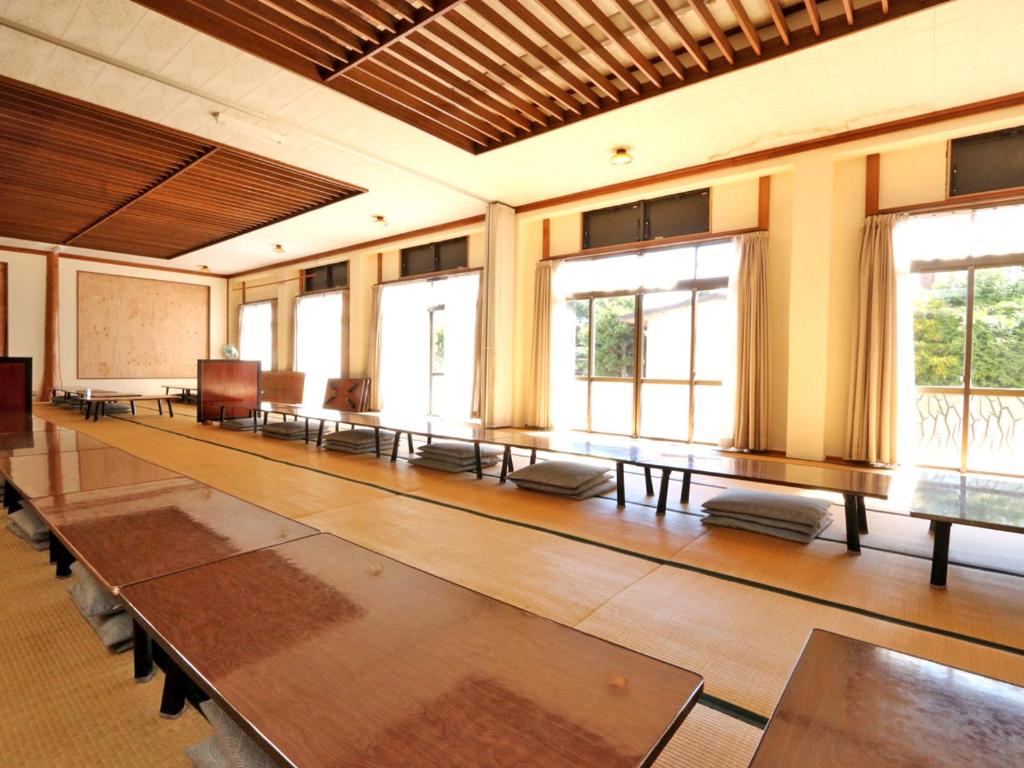 une grande pièce avec des tables, des chaises et des fenêtres dans l'établissement Sugakuso, à Yamanakako