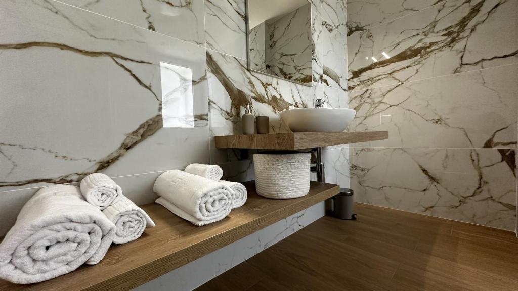La salle de bains est pourvue de serviettes blanches sur une étagère en bois. dans l'établissement Villa Pronti Santarcangelo - Rimini, à Santarcangelo di Romagna