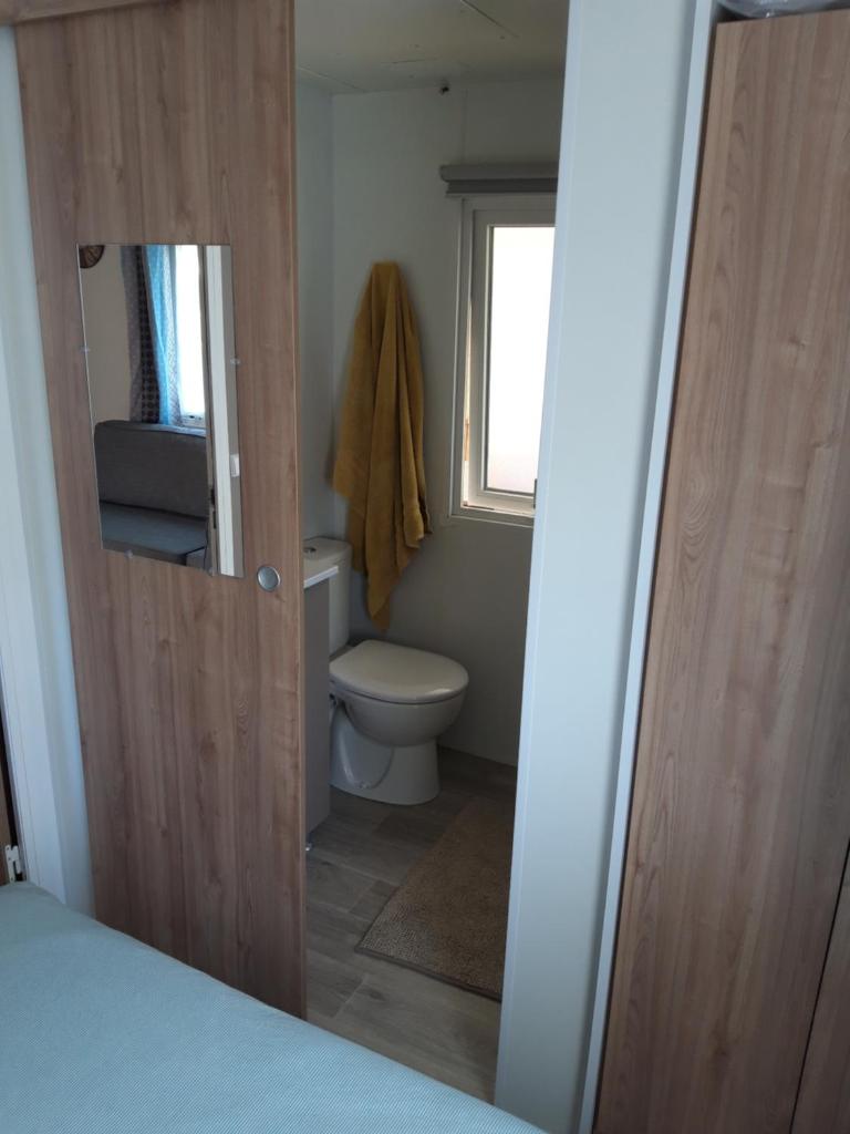 La salle de bains est pourvue de toilettes, d'une fenêtre et d'une porte. dans l'établissement mobilhome neuf et spacieux 6/8 pers., à Saint-Cyprien