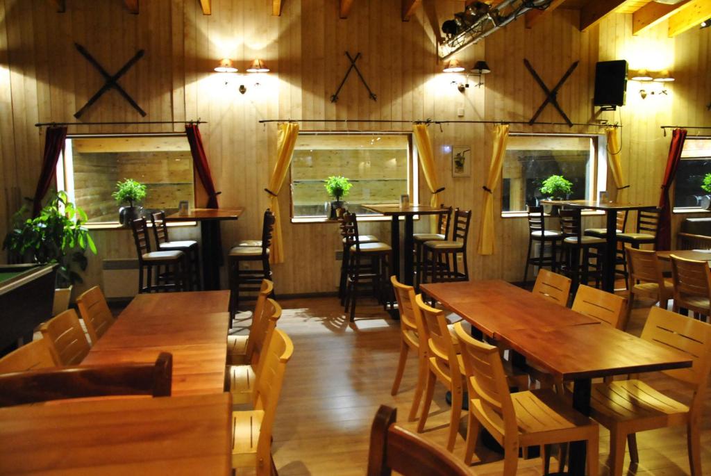 un restaurant avec des tables et des chaises en bois et des fenêtres dans l'établissement La Berangere, à Chamrousse