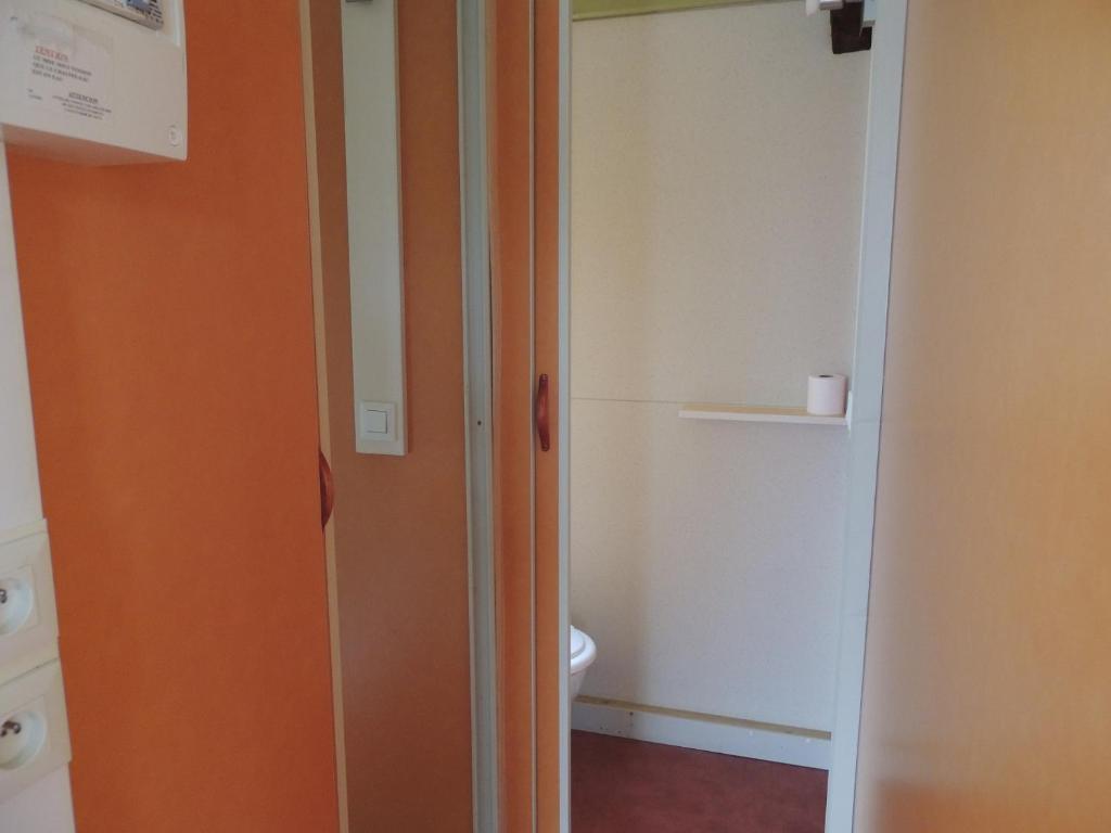 La salle de bains est pourvue d'une porte orange et de toilettes. dans l'établissement CHALET 4 personnes maxi tout confort location en gîte, à Chazemais