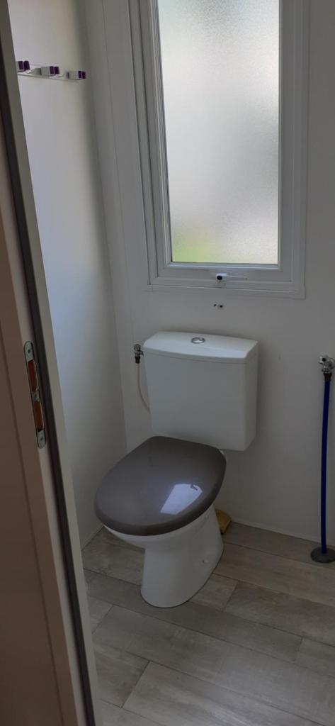 La salle de bains est pourvue de toilettes, d'une fenêtre et d'un miroir. dans l'établissement Ecrins Santé, à Valras-Plage