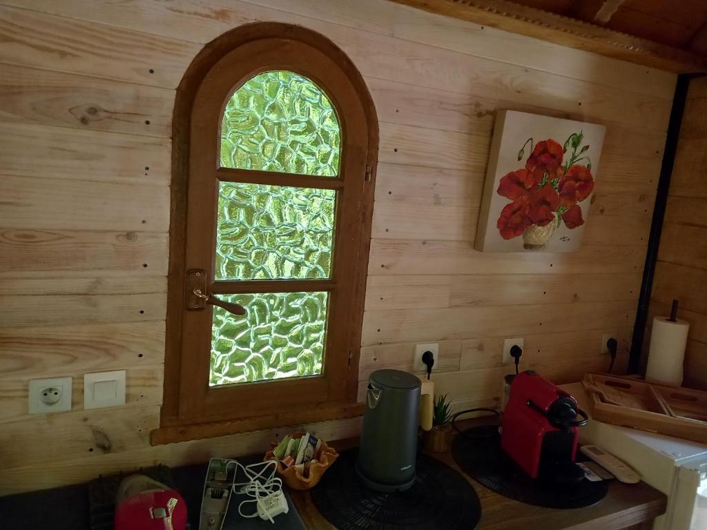 - une cuisine avec une fenêtre dans une cabane en rondins dans l'établissement La roulotte du petit paradis, à Saint-Rémy-de-Provence