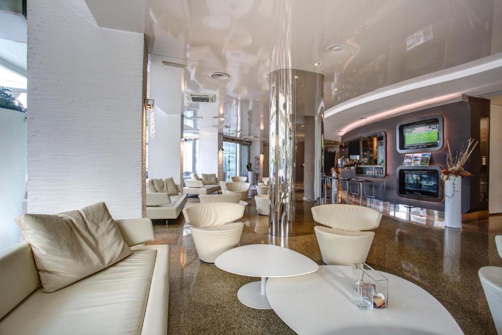 Cette chambre dispose d'un mobilier blanc, de tables et de chaises blanches. dans l'établissement Hotel Le Palme - Premier Resort, à Milano Marittima