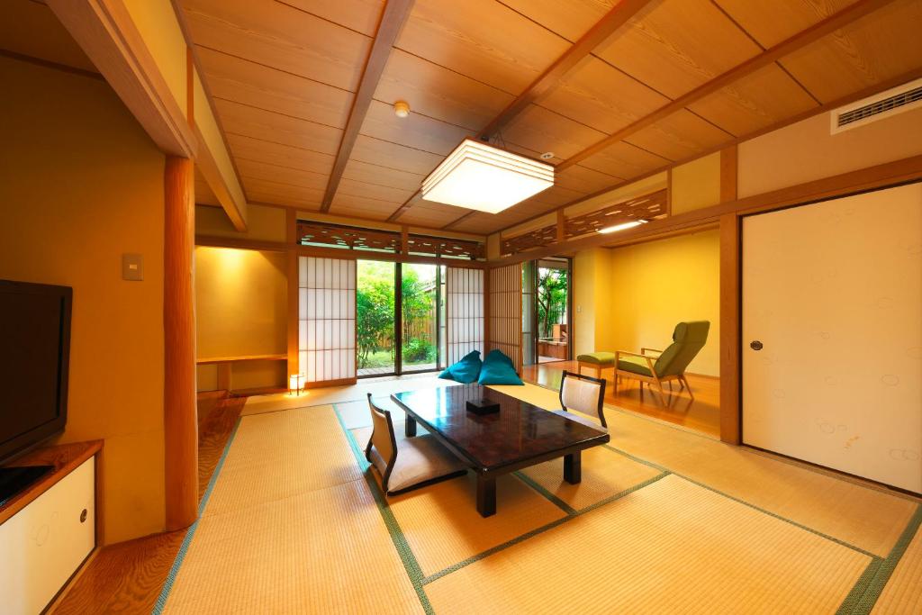 un salon avec une table, des chaises et une télévision dans l'établissement Kagetsutei, à Shimoda