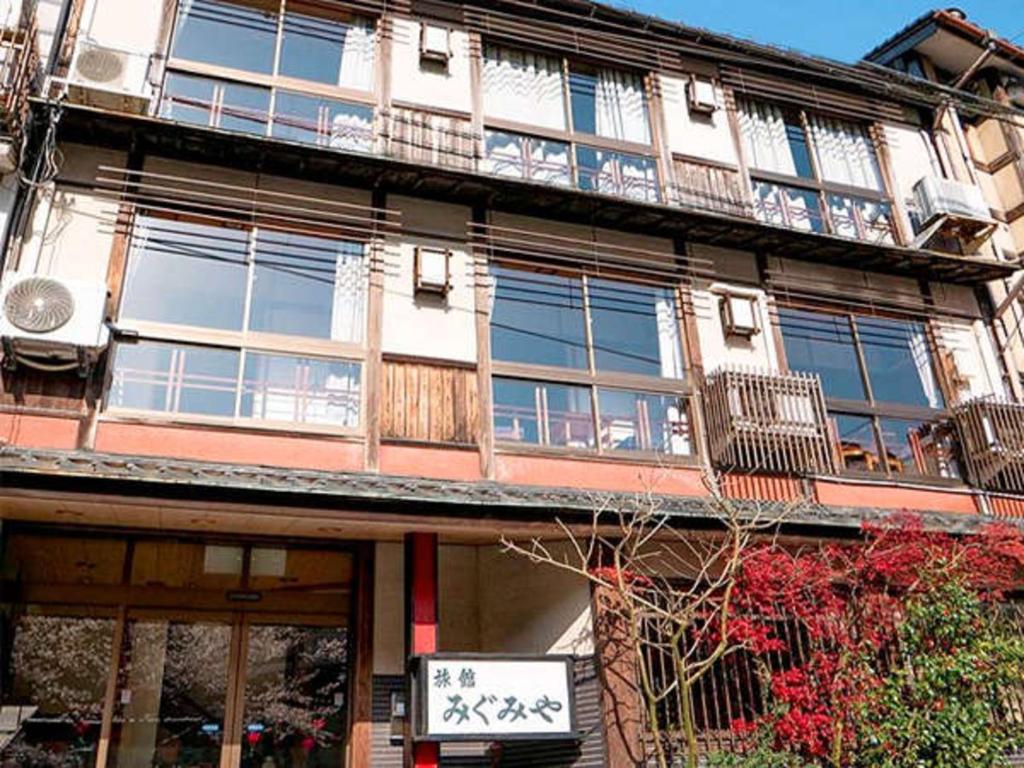 un bâtiment avec une enseigne devant lui dans l'établissement Migumiya Ryokan, à Toyooka