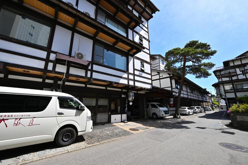une camionnette blanche garée devant un immeuble dans l'établissement Osakaya Ryokan, à Kusatsu