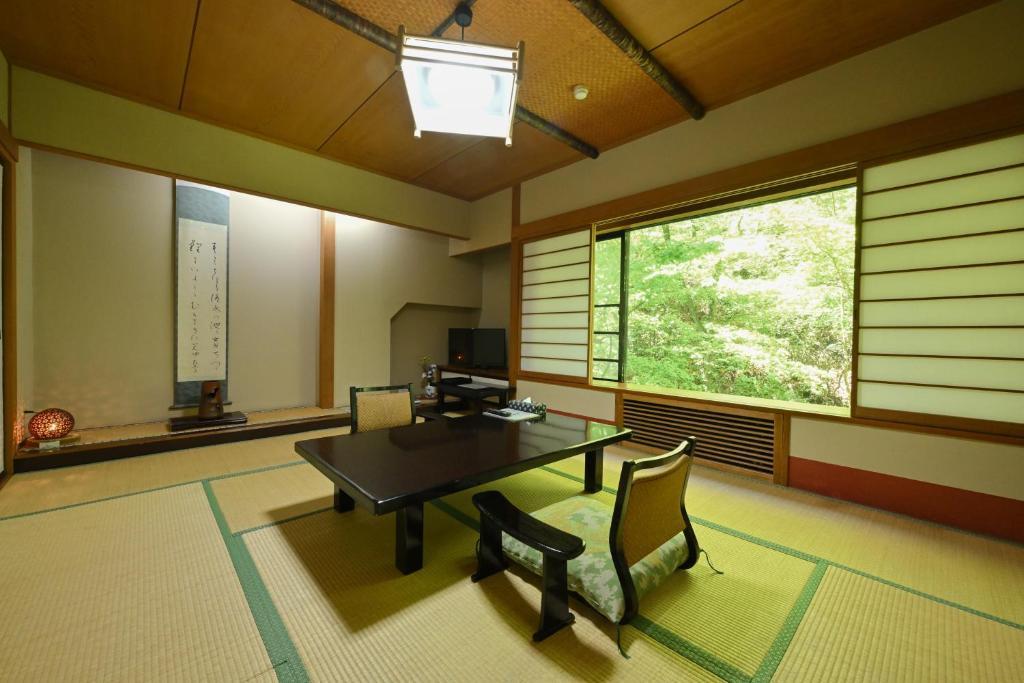 une pièce avec une table, des chaises et une fenêtre dans l'établissement Osakaya Ryokan, à Kusatsu