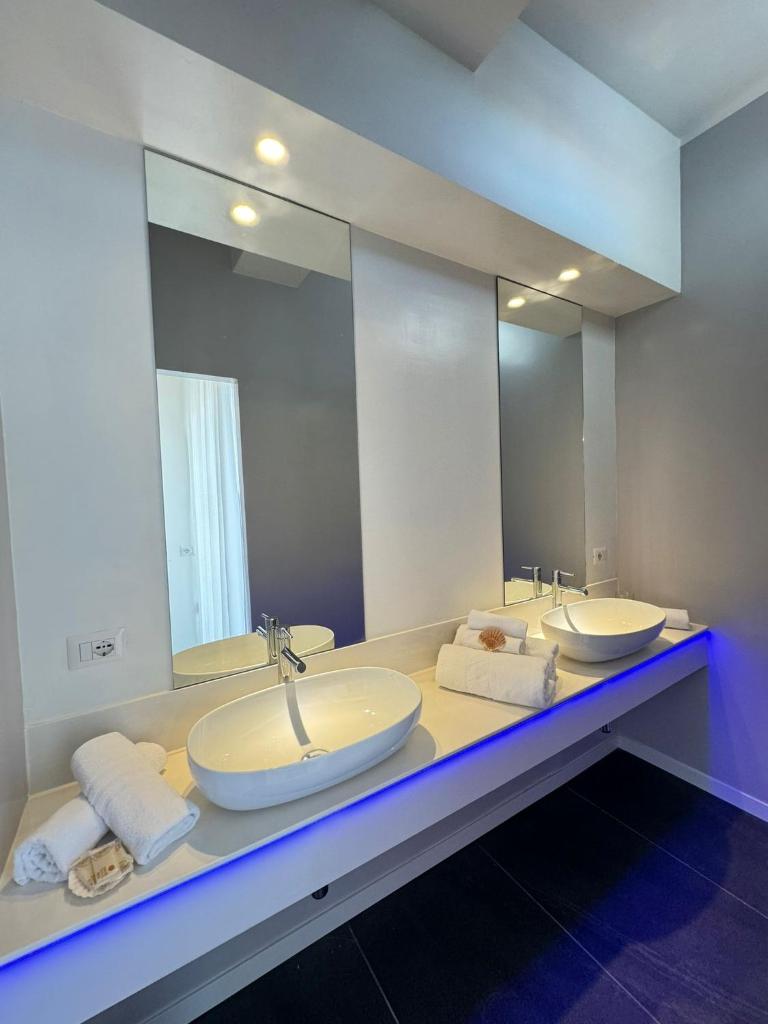 une salle de bain avec deux lavabos et un grand miroir dans l'établissement Hotel Pinocchio, à Cattolica