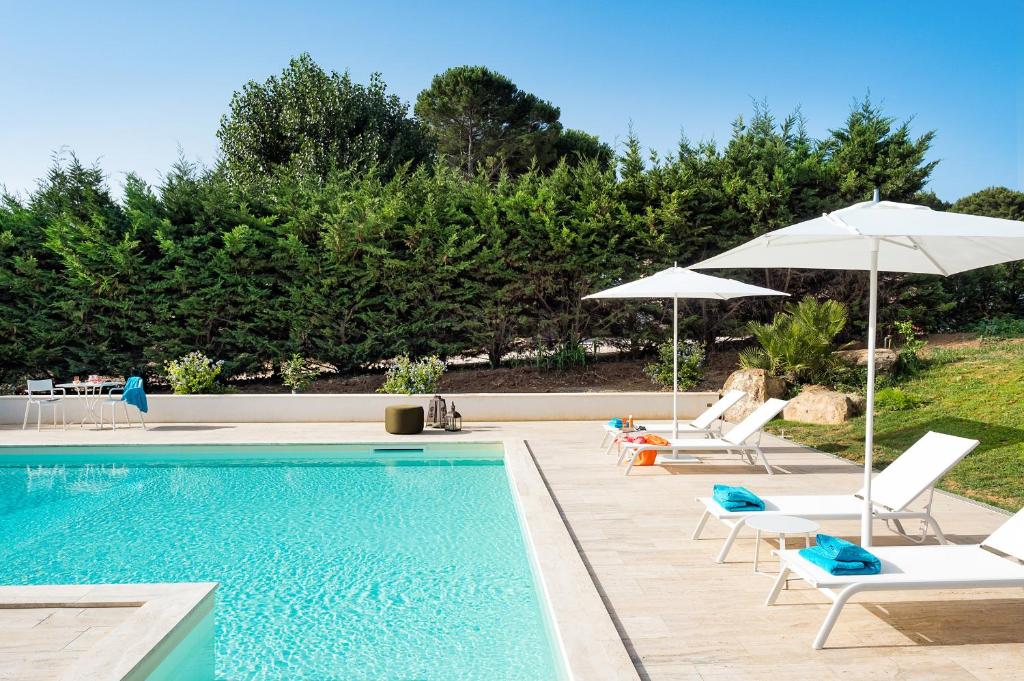 une piscine avec chaises longues et parasols dans l'établissement San Ciro, à Ulmi