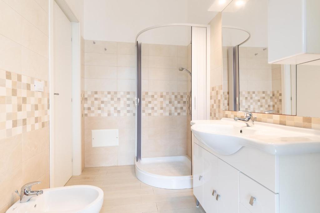 une salle de bain blanche avec deux lavabos et une douche dans l'établissement Villa Città Bianca, à Carovigno