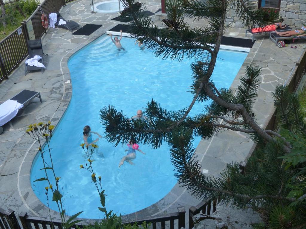 un groupe de personnes nageant dans une piscine dans l'établissement Le Grand Ours - Ski in ski out 4 bed chalet, Arc 1950, à Arc 1950