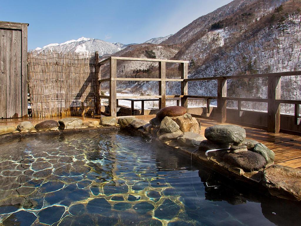 un bassin d'eau avec des montagnes en arrière-plan dans l'établissement Yukimurasaki, à Takayama