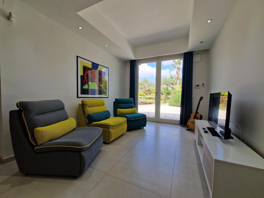 - un salon avec deux chaises et une télévision à écran plat dans l'établissement Villa Virginia - Relax and Private Pool, à Paceco