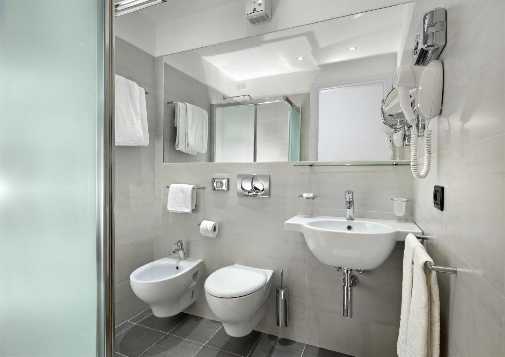 une salle de bain blanche avec un lavabo et des toilettes dans l'établissement Hotel Bellavista, à Lignano Sabbiadoro