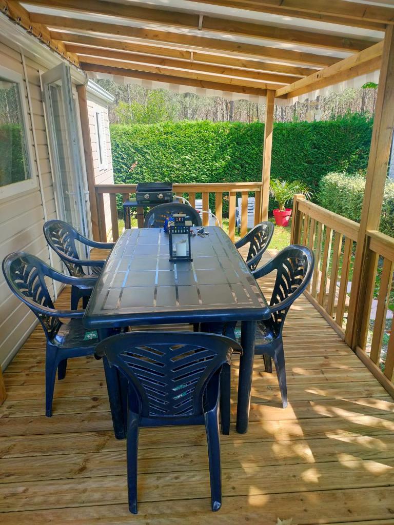 une table et des chaises sur une terrasse en bois dans l'établissement Mobil home, camping 4* Lac privé, à Gastes