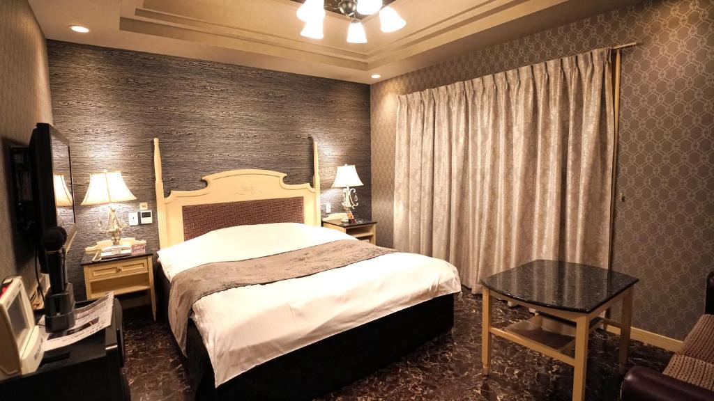 une chambre d'hôtel avec un lit et une table dans l'établissement アンブレイン堺, à Sakai