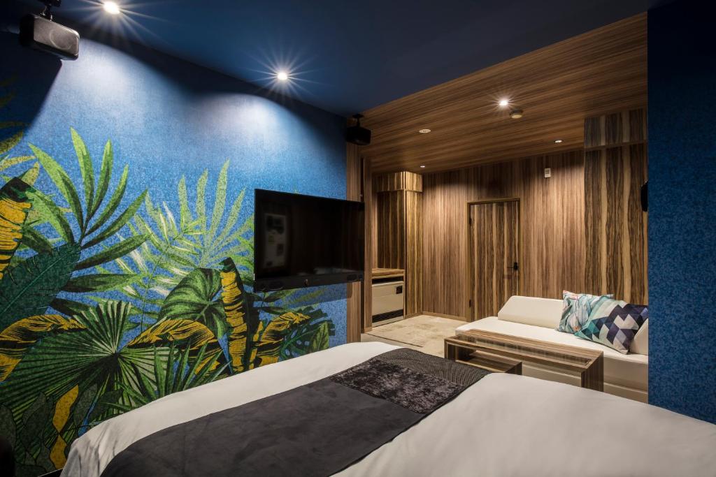 une chambre avec un lit, une télévision et un canapé dans l'établissement Hotel Chroma - Adult Only, à Ueda