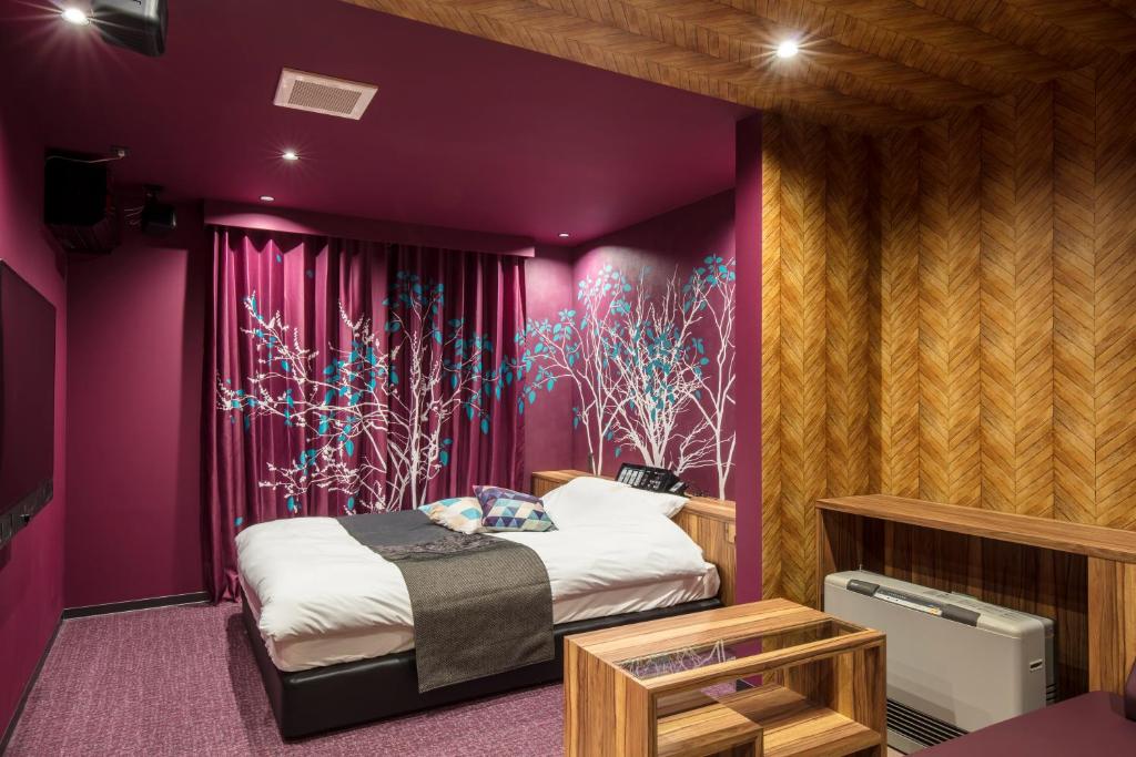 une chambre avec un lit et un mur violet dans l'établissement Hotel Chroma - Adult Only, à Ueda