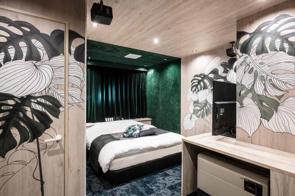 - une chambre avec un lit et un mur orné de plantes dans l'établissement Hotel Chroma - Adult Only, à Ueda