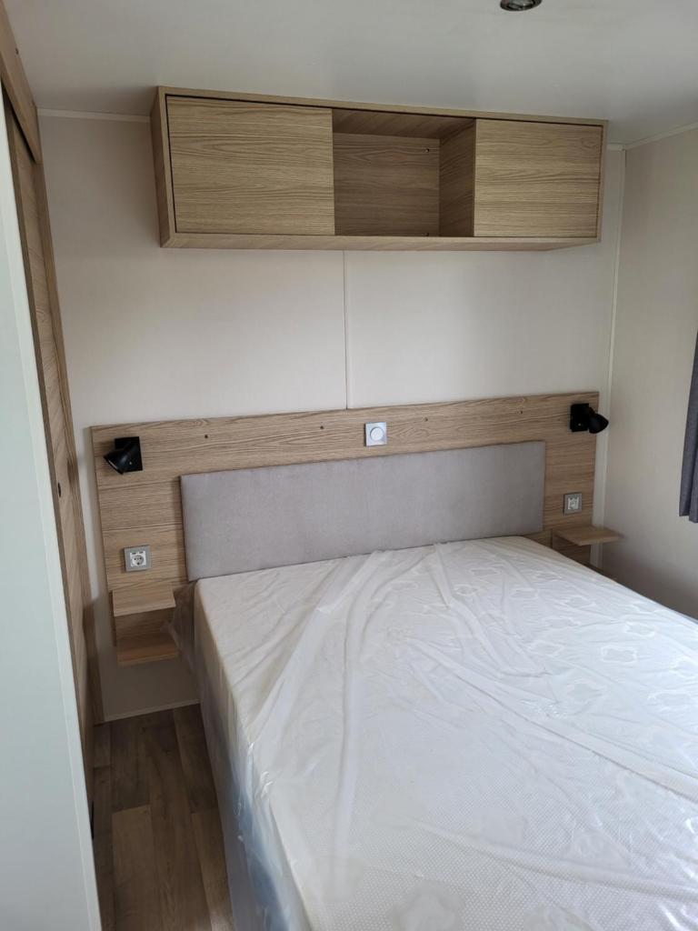 - une petite chambre avec un lit et des placards en bois dans l'établissement Mobil-home à Lattes, à Lattes
